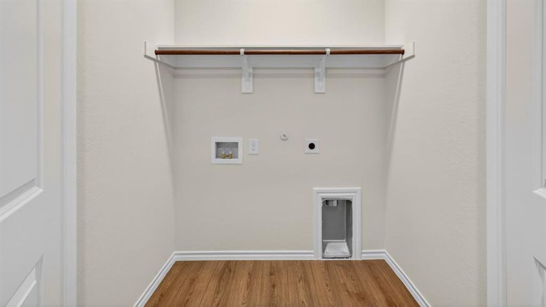 Dedicated laundry area featuring wood-finish flooring, light neutral wall paint, and a built-in shelving unit