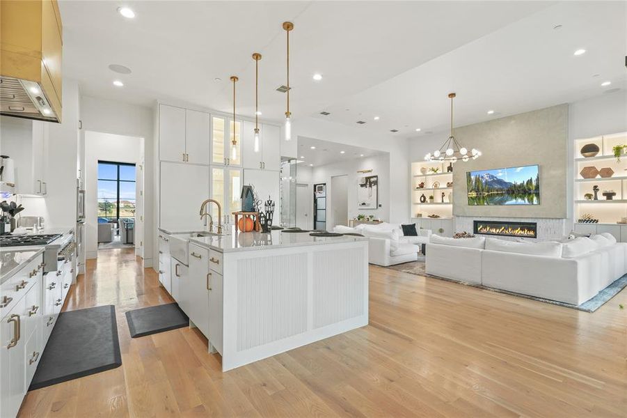 Kitchen featuring white cabinetry, decorative light fixtures, open floor plan, light wood-type flooring, and recessed lighting Kitchen featuring white cabinetry, decorative light fixtures, open floor plan, light wood-type flooring, and recessed lighting