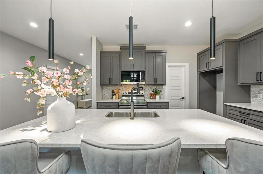 Kitchen featuring a kitchen breakfast bar, gray cabinets, light stone counters, and recessed lighting Kitchen featuring a kitchen breakfast bar, gray cabinets, light stone counters, and recessed lighting