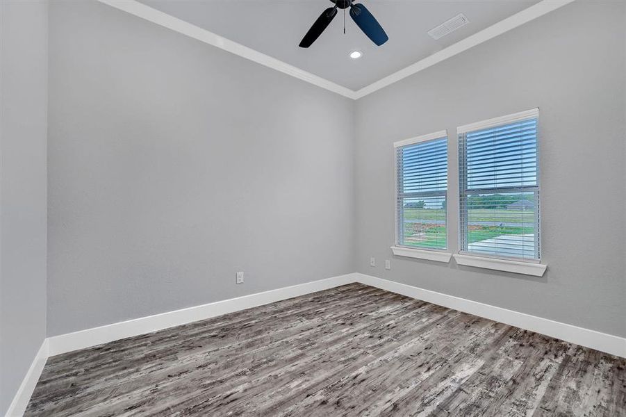 Empty room with wood-type flooring, crown molding, and ceiling fan