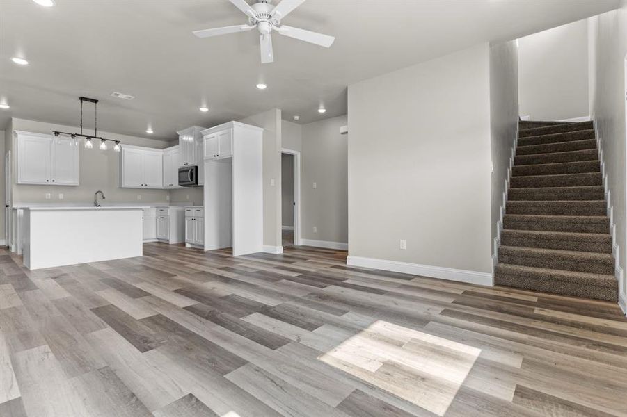 Unfurnished living room featuring recessed lighting, a ceiling fan, stairway, baseboards, and light wood-type flooring Unfurnished living room featuring recessed lighting, a ceiling fan, stairway, baseboards, and light wood-type flooring