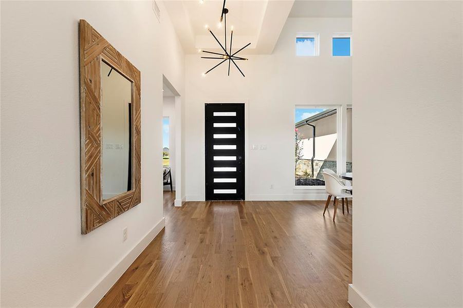 Foyer featuring soaring ceilings, a contemporary chandelier, and wood-finish flooring Foyer featuring soaring ceilings, a contemporary chandelier, and wood-finish flooring