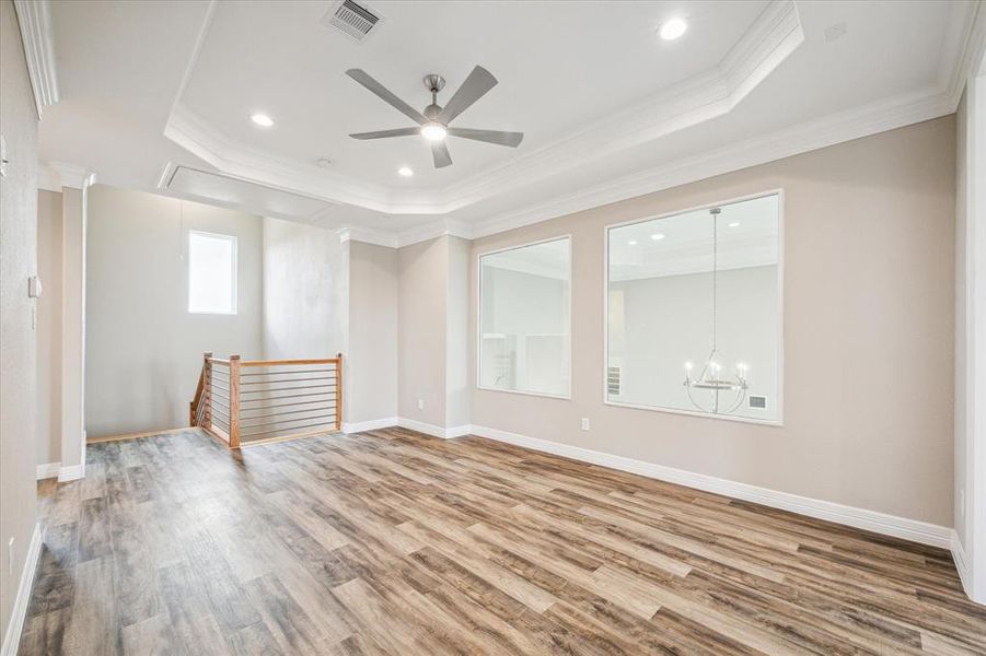 This is a spacious, well-lit room with elegant tray ceilings, modern wood flooring, and large windows.  A perfect game room!