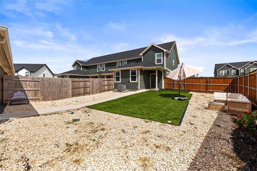 A well-maintained fenced yard offers a blend of green lawn and practical gravel, perfect for outdoor enjoyment.