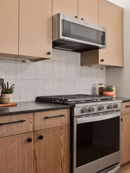 Kitchen with dark countertops, stainless steel appliances, and tasteful backsplash