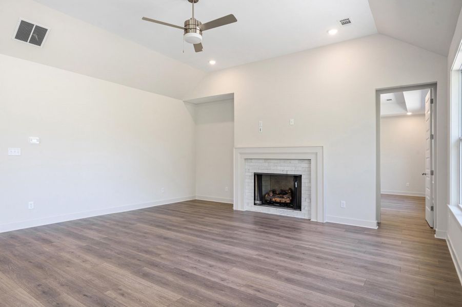 Unfurnished living room with ceiling fan, lofted ceiling, dark wood-type flooring, recessed lighting, and a fireplace
