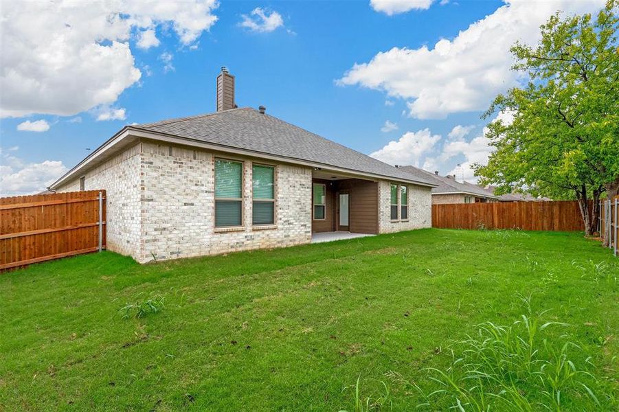 Back of property featuring a lawn and a patio area