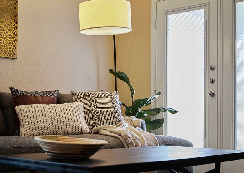 Living room with a comfortable gray couch with decorative pillows, a wood coffee table, and French doors leading to the back patio.