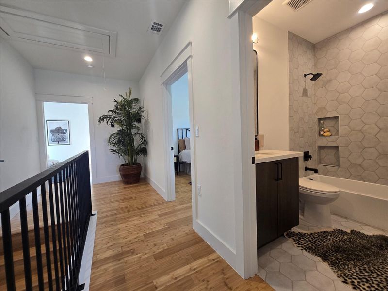 Rich wood flooring connects the upper landing to a beautifully tiled bathroom.