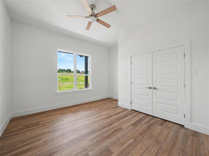 Room featuring wood-finish flooring, a contemporary ceiling fan, and white baseboards