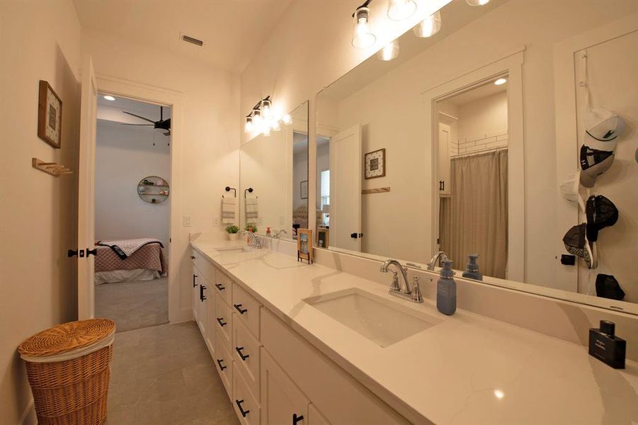 Ensuite bathroom featuring double vanity and light tile patterned floors