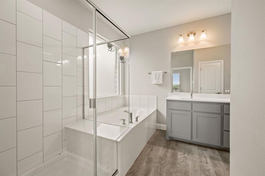 Primary bathroom retreat with a soaking tub, separate glass-enclosed shower, and modern vanity with storage.