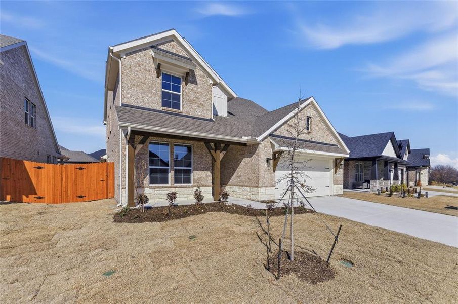 View of front facade featuring a porch, brick siding, driveway, roof with shingles, and an attached garage
