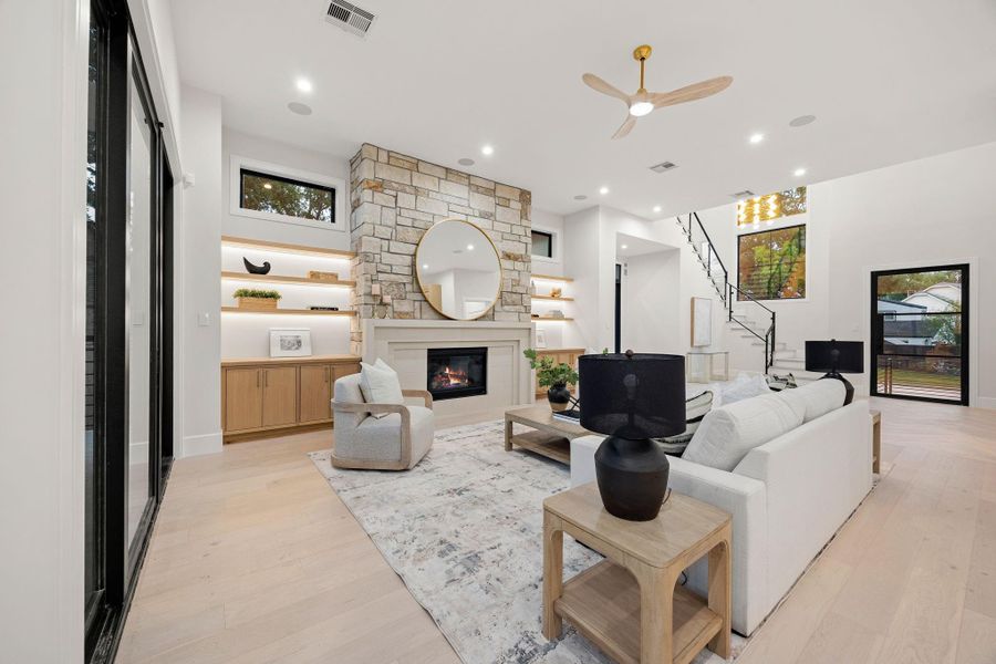 A spacious living area designed with both scale and comfort in mind, offering multiple seating options and clear views across the open floor plan. High ceilings and recessed lighting enhance the sense of openness, while large windows bring in consistent natural light. The layout encourages connection while still allowing for defined spaces, making it ideal for both quiet evenings and lively gatherings.