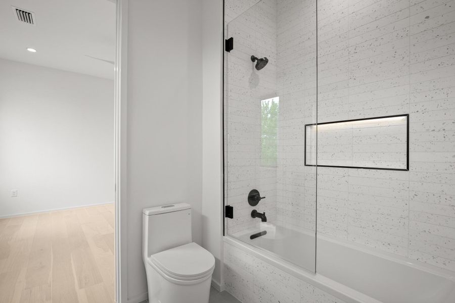 Bathroom with bathing tub / shower combination and light wood-type flooring