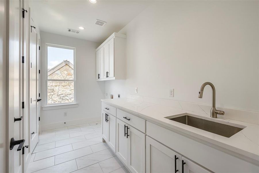 Laundry room featuring light tile flooring, washer hookup, hookup for an electric dryer, sink, and cabinets