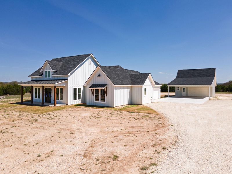 Modern inspired farmhouse featuring an outbuilding, a shingled roof, driveway, and covered porch
