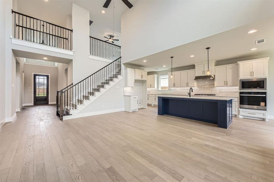 Kitchen with stainless steel oven, under cabinet range hood, ceiling fan, built in microwave, and healthy amount of natural light