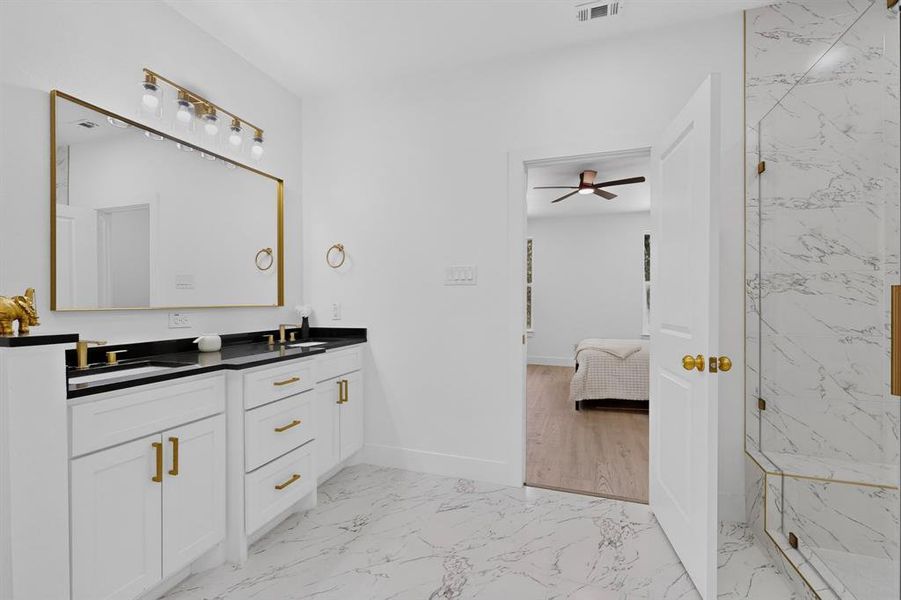Bathroom featuring a double vanity with black countertops and white cabinetry