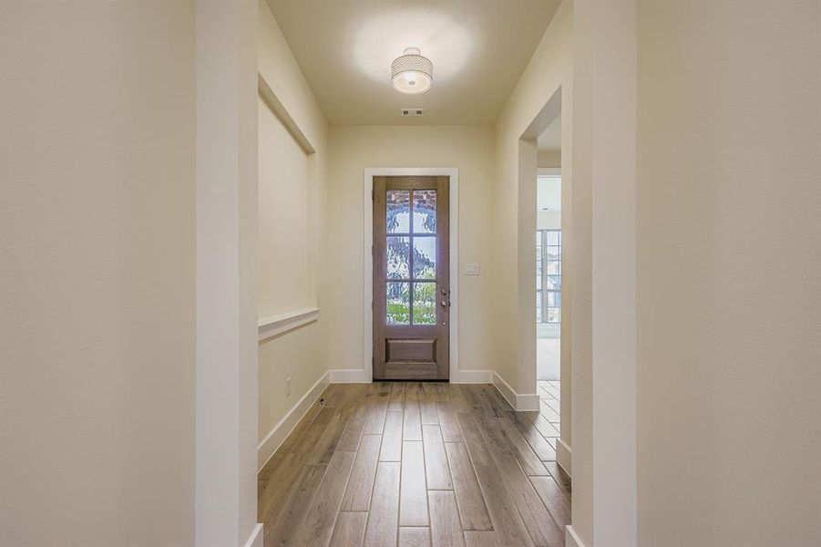 Doorway with wood finished floors and baseboards