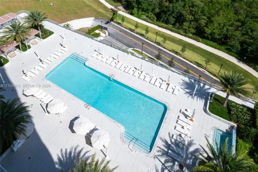 Rectangular swimming pool with integrated spa, expansive paved decking, and perimeter glass railing