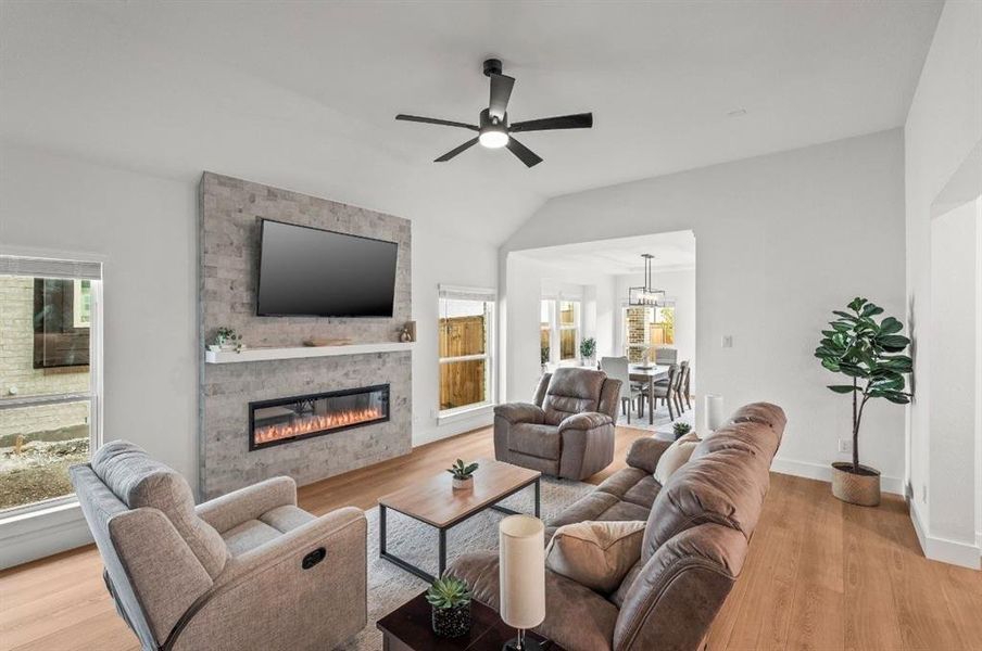 Living room with light wood-style flooring, a fireplace, vaulted ceiling, and ceiling fan Living room with light wood-style flooring, a fireplace, vaulted ceiling, and ceiling fan