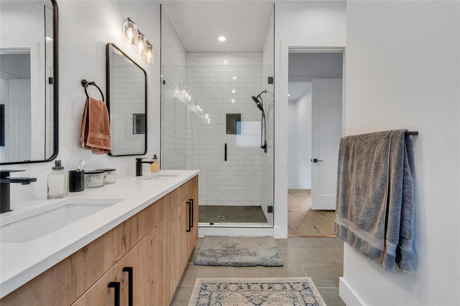 Full bathroom featuring double vanity, a stall shower, and light tile patterned floors Full bathroom featuring double vanity, a stall shower, and light tile patterned floors