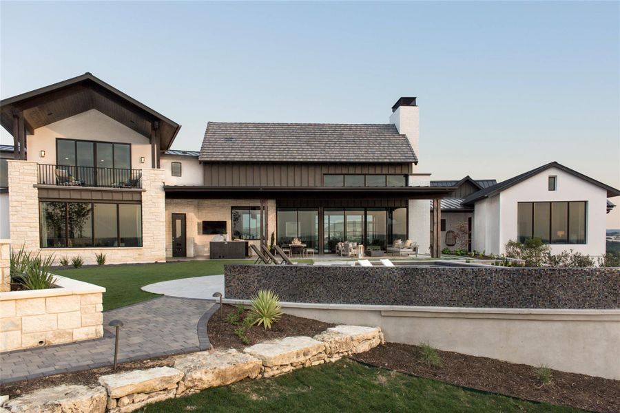 Rear view of property featuring a standing seam roof, a patio, a metal roof, a balcony, and a chimney