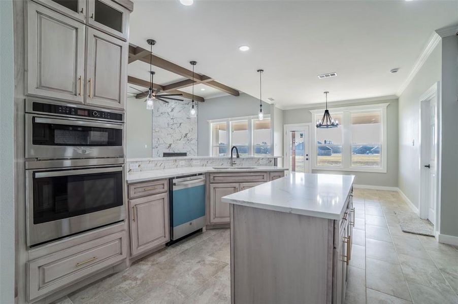 Kitchen with stainless steel double oven, hanging light fixtures, dishwashing machine, beam ceiling, and plenty of natural light Kitchen with stainless steel double oven, hanging light fixtures, dishwashing machine, beam ceiling, and plenty of natural light