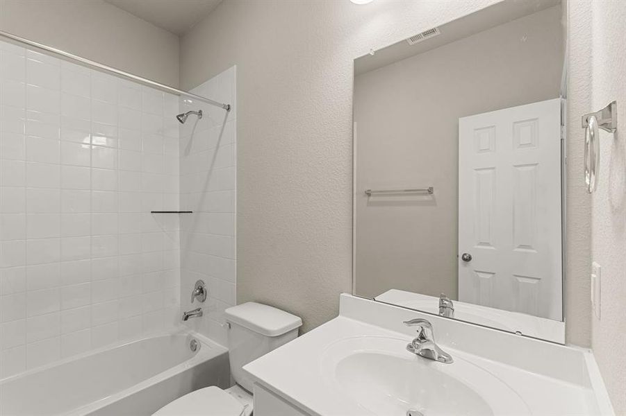 The secondary bath features tile flooring, white cabinetry and light countertops and a shower/tub combo. Perfect for accommodating any visiting family and friends.