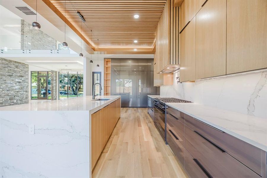 Kitchen with modern cabinets, light stone countertops, light wood-type flooring, gas stove, and wood ceiling Kitchen with modern cabinets, light stone countertops, light wood-type flooring, gas stove, and wood ceiling