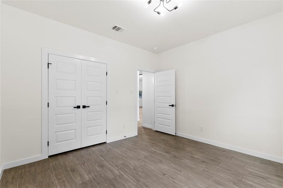 Interior space featuring wood-finish flooring, white walls, and a contemporary ceiling light fixture