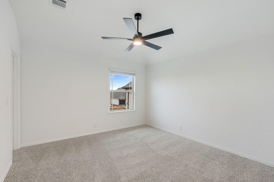 Empty bedroom with gray carpet, white walls, black ceiling fan, and single window
