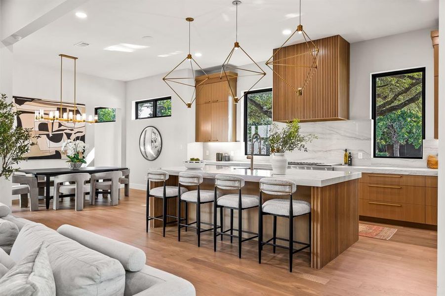 Kitchen with a kitchen island with sink, a breakfast bar area, decorative light fixtures, modern cabinets, and recessed lighting Kitchen with a kitchen island with sink, a breakfast bar area, decorative light fixtures, modern cabinets, and recessed lighting