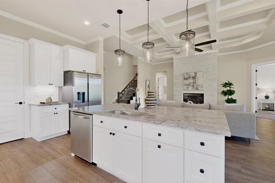 Kitchen island with stone countertop, white shaker cabinetry, stainless steel appliances, wood-finish flooring, and coffered ceiling