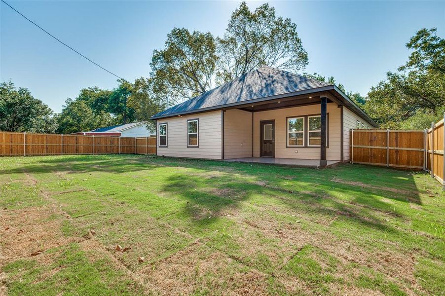 Back of property featuring a fenced backyard, a patio, and roof with shingles