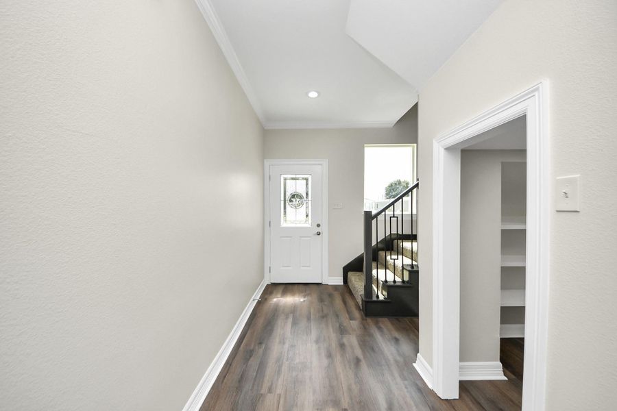 Another look at the bright and inviting foyer, featuring an impressive under-stairs niche that adds both charm and practical storage. This thoughtful detail blends style and function, making a great first impression the moment you enter - (representation photo).