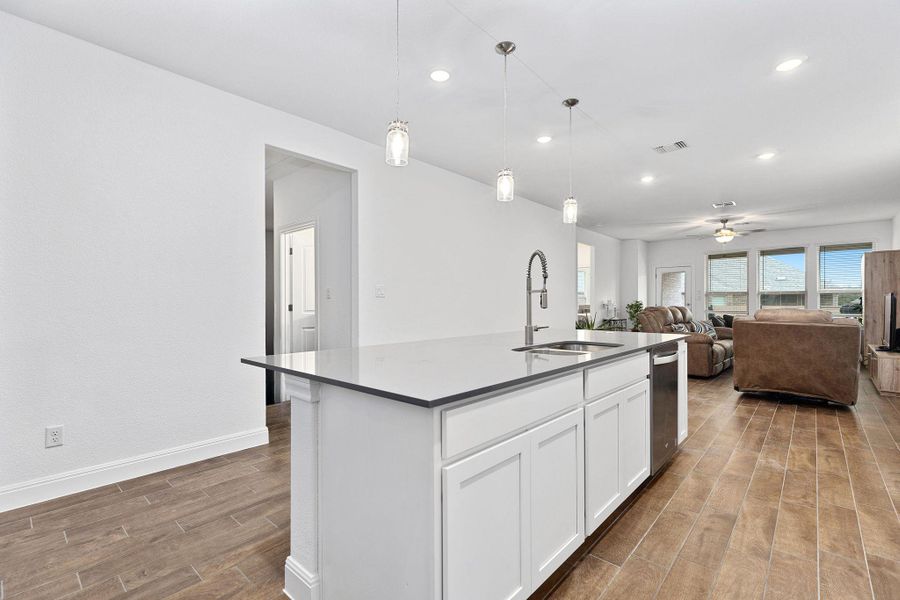A streamlined kitchen island with a sleek countertop and contemporary lighting creates an inviting open-concept living space.