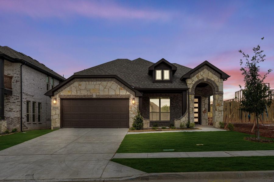 Single-story home with stone and brick exterior, two-car garage, and arched entryway at dusk