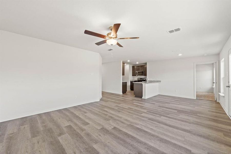 Unfurnished living room with ceiling fan and light hardwood / wood-style flooring