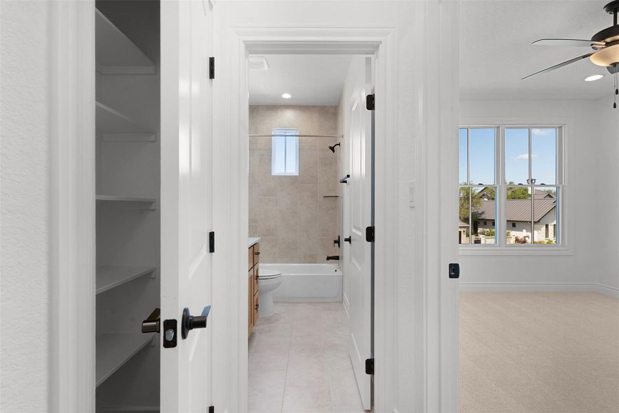 View into a bathroom with a shower-bathtub combination, tiled floors, and a window