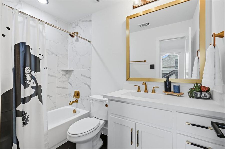 Upstairs ensuite bathroom with shower / bath combo and vanity with gold touches & black tiled flooring Upstairs ensuite bathroom with shower / bath combo and vanity with gold touches & black tiled flooring