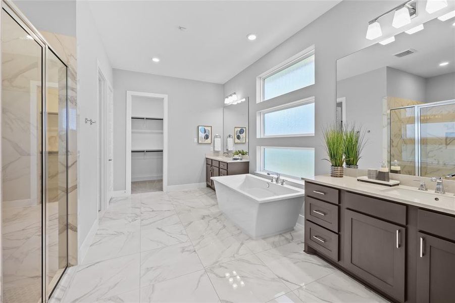 Primary bathroom with separate soaking tub, large walk in shower, and 2 primary closets