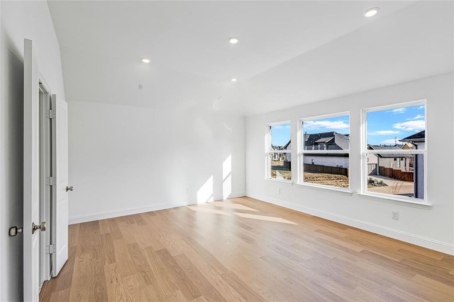 Spare room with lofted ceiling and light wood-type flooring