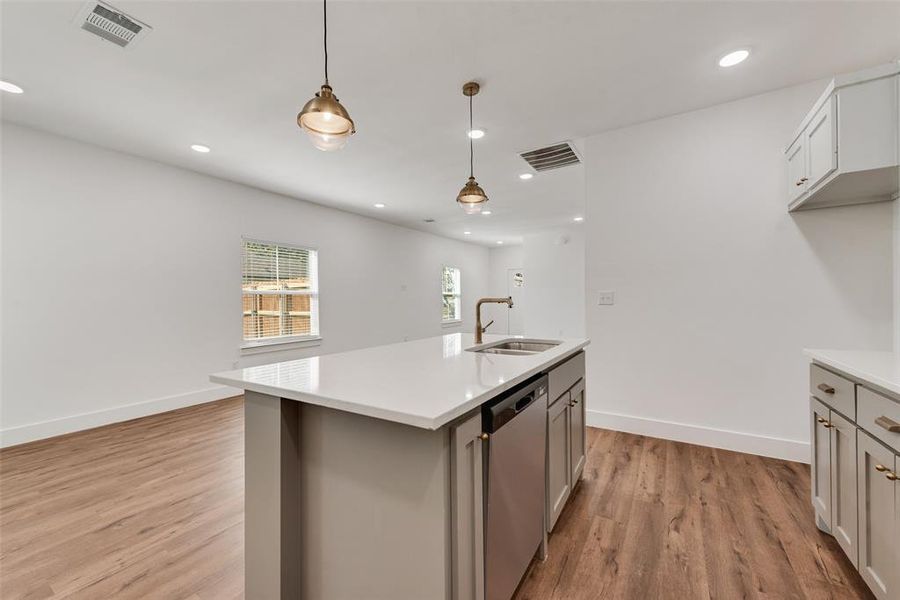 Kitchen with hanging light fixtures, light wood-style flooring, stainless steel dishwasher, recessed lighting, and gray cabinets Kitchen with hanging light fixtures, light wood-style flooring, stainless steel dishwasher, recessed lighting, and gray cabinets