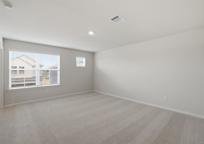 Primary bedroom featuring windows with natural light, carpet flooring, and neutral wall color.