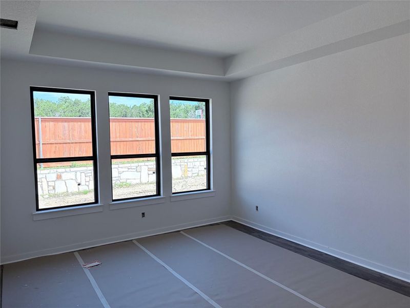 A new construction bedroom boasts three large windows and a clean tray ceiling. A new construction bedroom boasts three large windows and a clean tray ceiling.