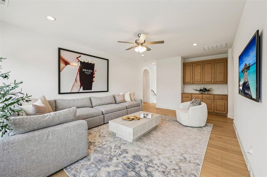Spacious living area featuring light wood-finish flooring, recessed lighting, and a ceiling fan