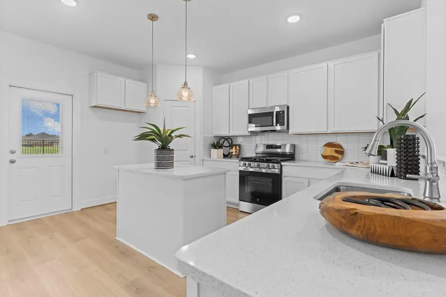 This extended countertop and extra cabinetry area offers even more functionality and prep space—ideal for a coffee bar, serving station, or display shelf. A glass door provides backyard access just steps away. **Image Representative of Plan Only and May Vary as Built**.