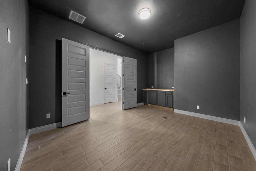 Versatile flex room with dark walls and wood-look flooring, ideal for a media space, home office, or game room.
